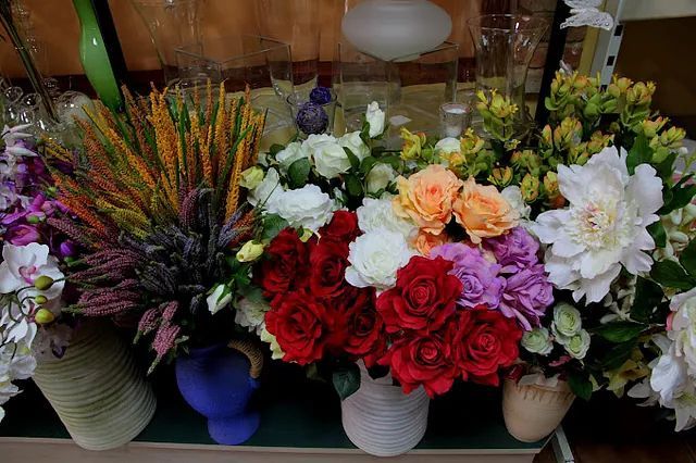 Hay muchos tipos diferentes de flores en los jarrones sobre la mesa.