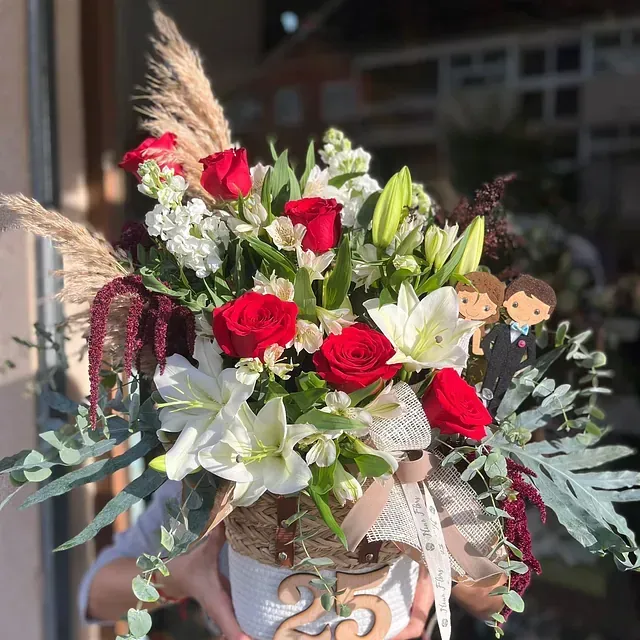 Una persona sostiene un jarrón de flores con el número 25.