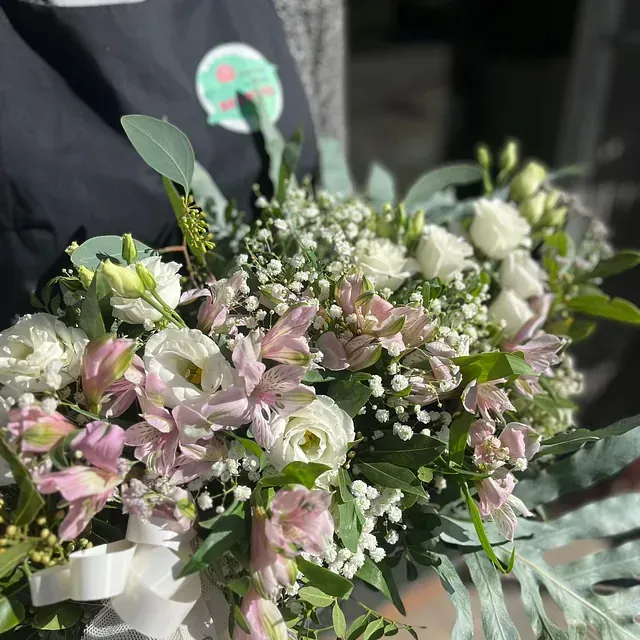 Una persona sostiene un ramo de flores rosas y blancas.