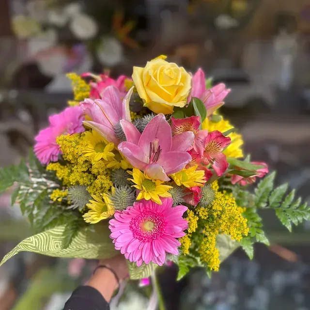 Una persona sostiene un ramo de flores rosas y amarillas.