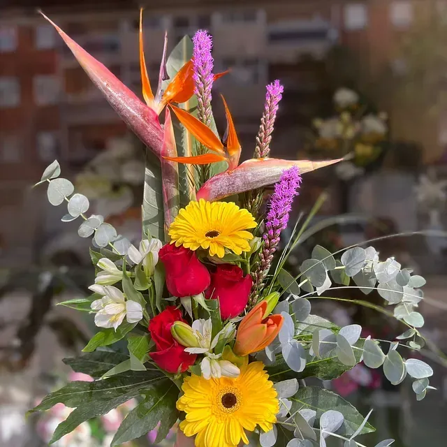 Un ramo de flores que incluye margaritas amarillas y rosas rojas.