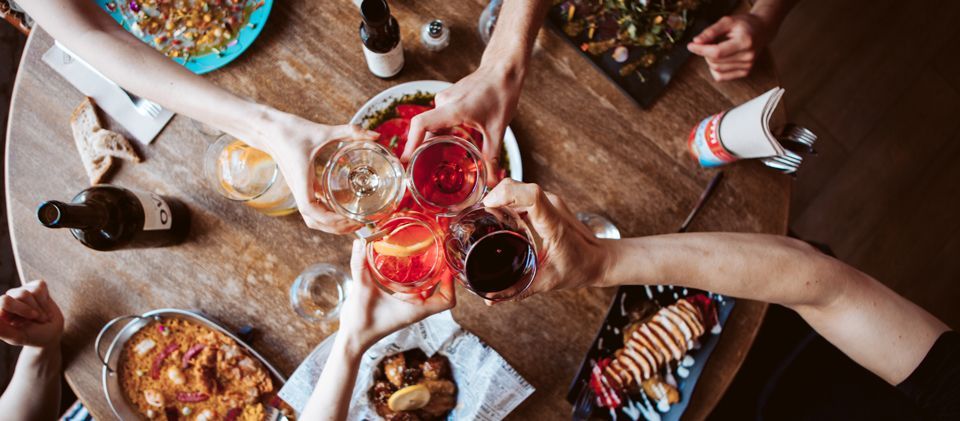 Un grupo de personas están sentadas alrededor de una mesa brindando con copas de vino.