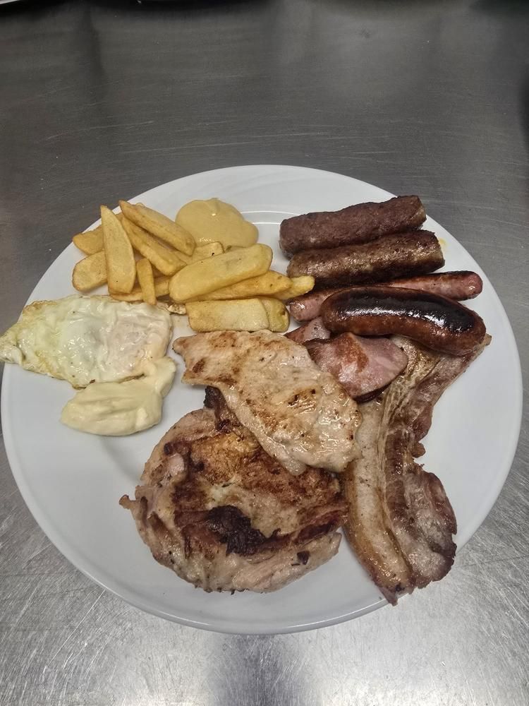 Un plato de comida que contiene patatas fritas, un huevo y una variedad de carnes a la parrilla