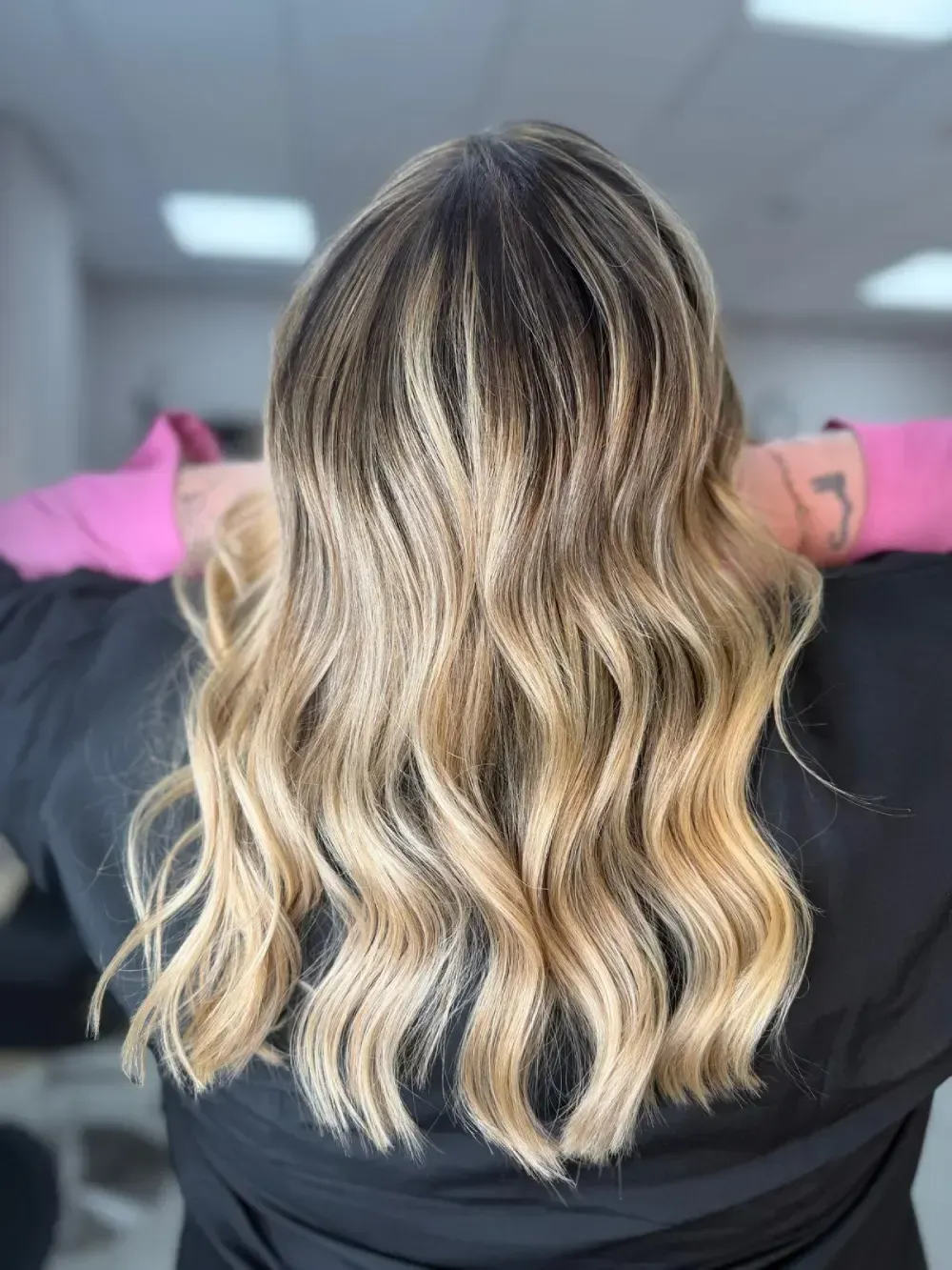 Una mujer con cabello rubio largo y ondulado mira a la cámara, 