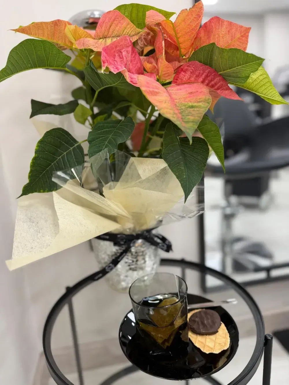 Mujer con cabello ondulado, desde raíces oscuras hasta puntas rubias, de pie en el interior.