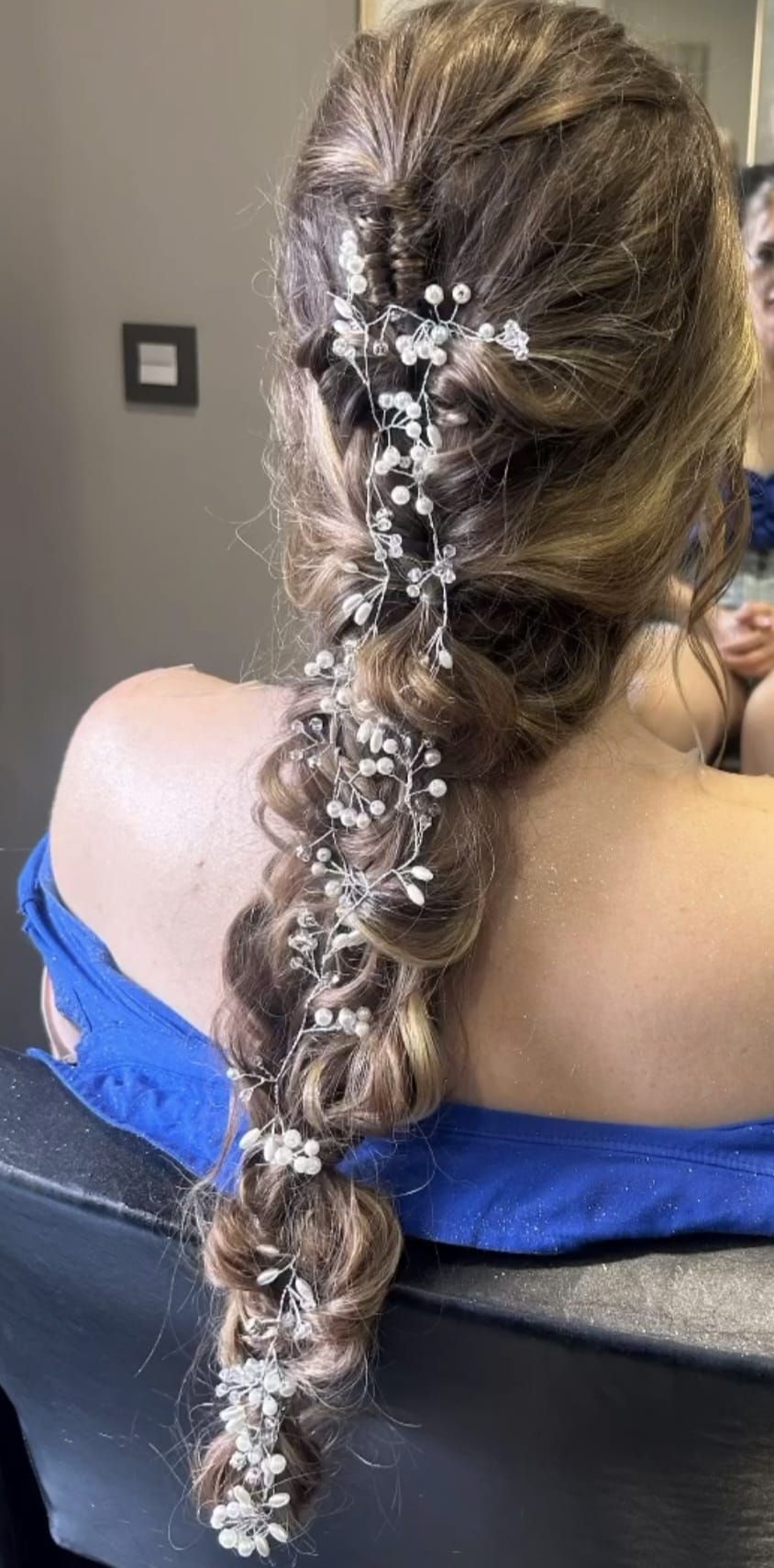 Mujer con cabello castaño ondulado, peinado con un elegante recogido, vista de espaldas. 