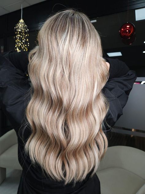 Mujer con cabello castaño largo y rizado, mirando hacia la derecha, vistiendo una blusa rosa claro, sobre un fondo azul.
