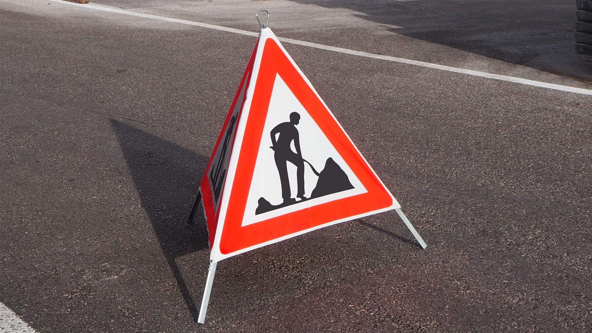 Auf einer Bau- oder Abrissbaustelle lädt ein gelber Bagger Bauschutt auf die Ladefläche eines grossen, roten Muldenkippers.