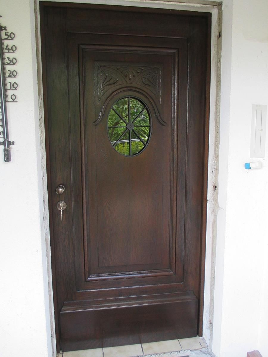 Eine Holztür mit einem runden Fenster und einem Thermometer dahinter