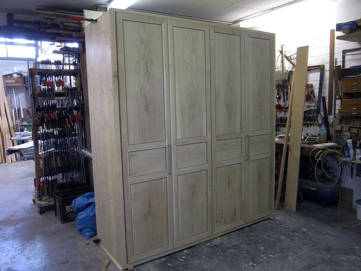 Ein großer Holzschrank steht in einer Werkstatt