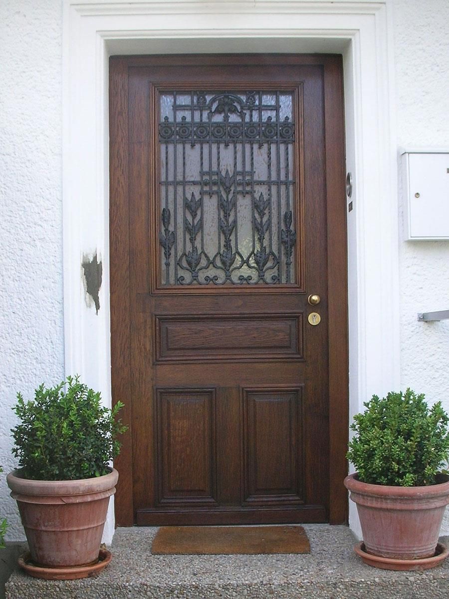 Zwei Topfpflanzen stehen vor einer Holztür