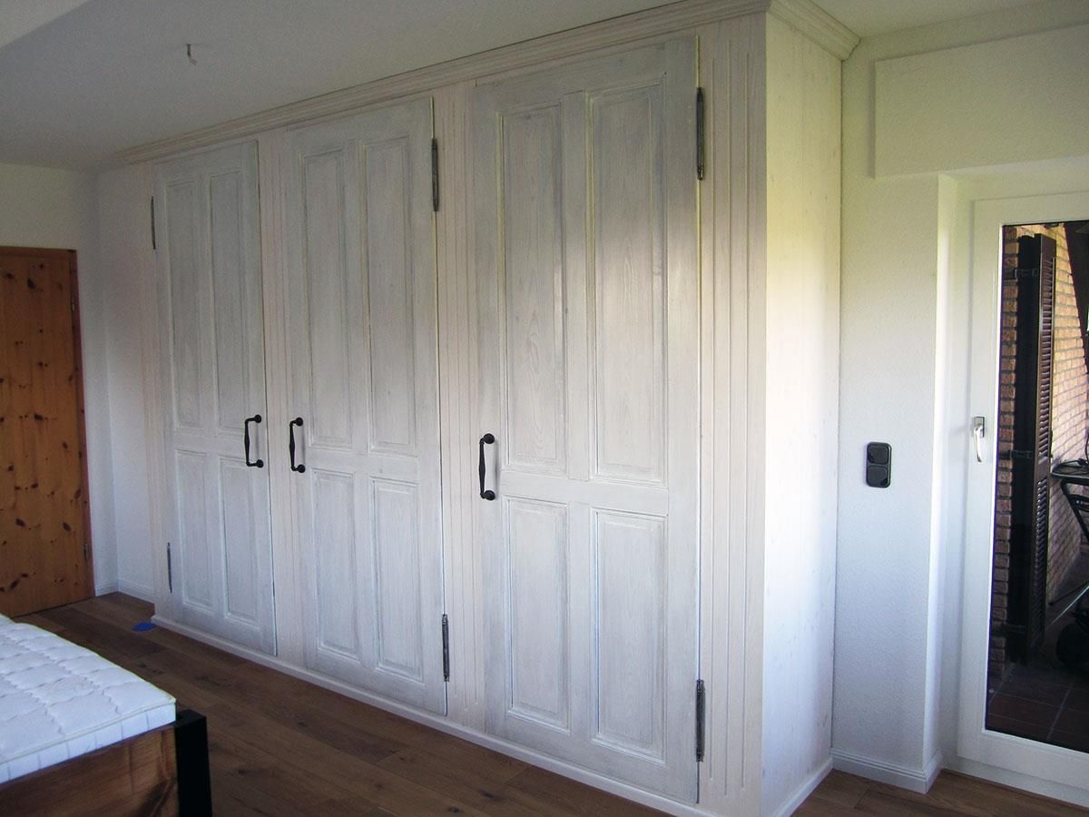 Ein Schlafzimmer mit weißen Schränken und einem Spiegel