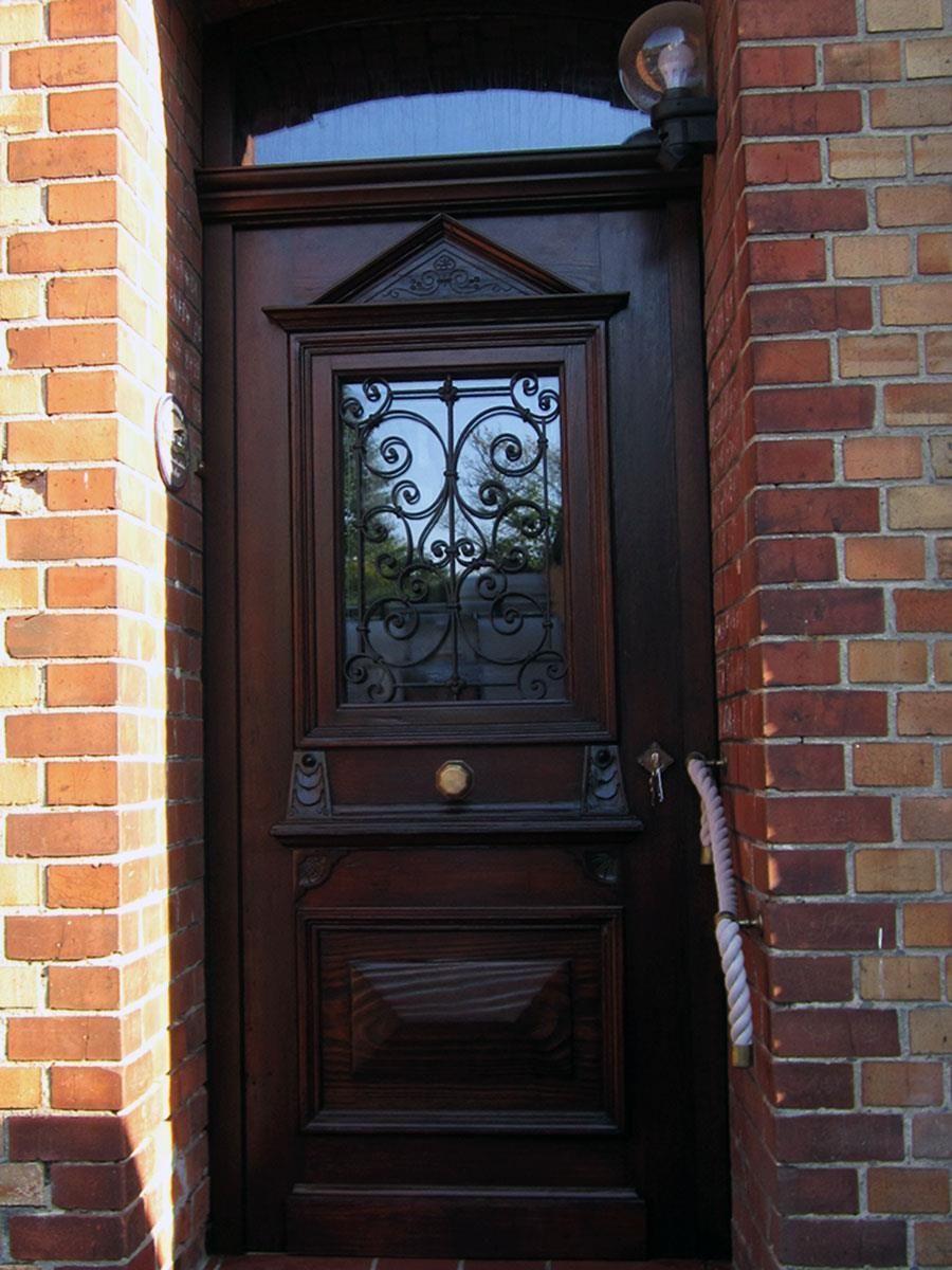 Ein Backsteingebäude mit einer Holztür mit einem schmiedeeisernen Fenster