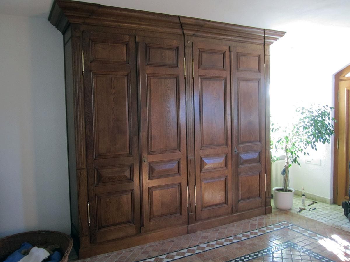 Ein großer Holzschrank mit vier Türen steht in einem Raum