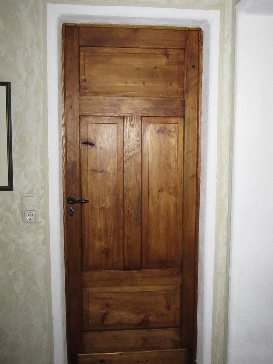 Eine Holztür steht vor einer weißen Wand