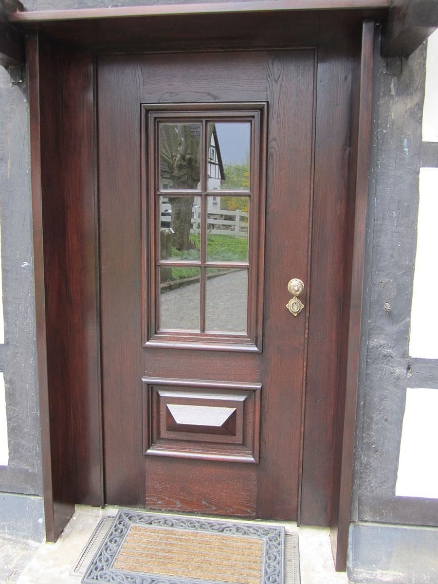 Eine Holztür mit der Spiegelung eines Hauses darin