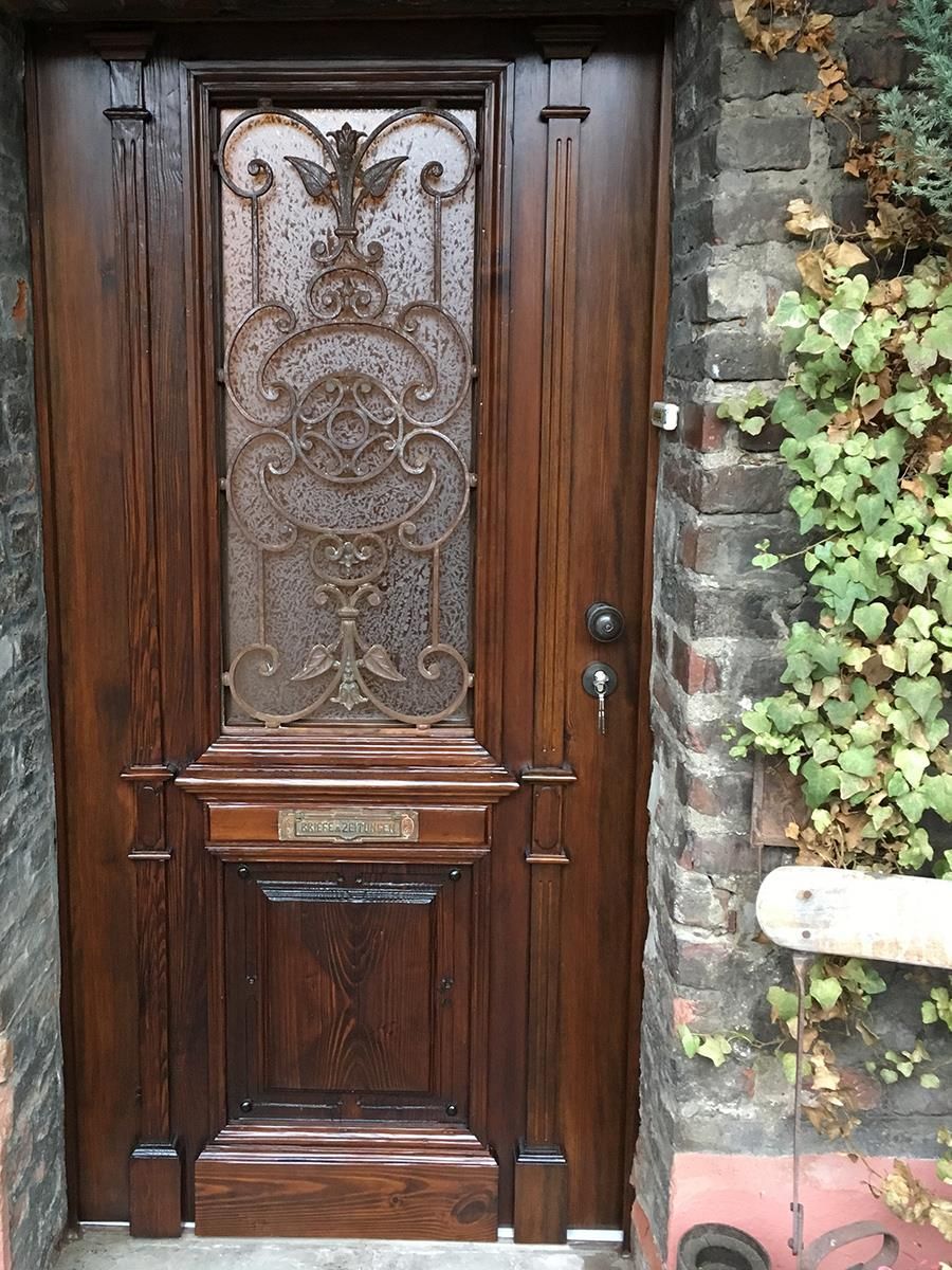 Eine Holztür mit einem Buntglasfenster steht an einer Ziegelwand