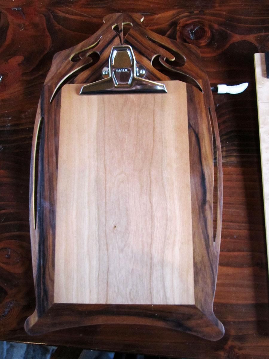 Ein hölzernes Klemmbrett liegt auf einem Holztisch