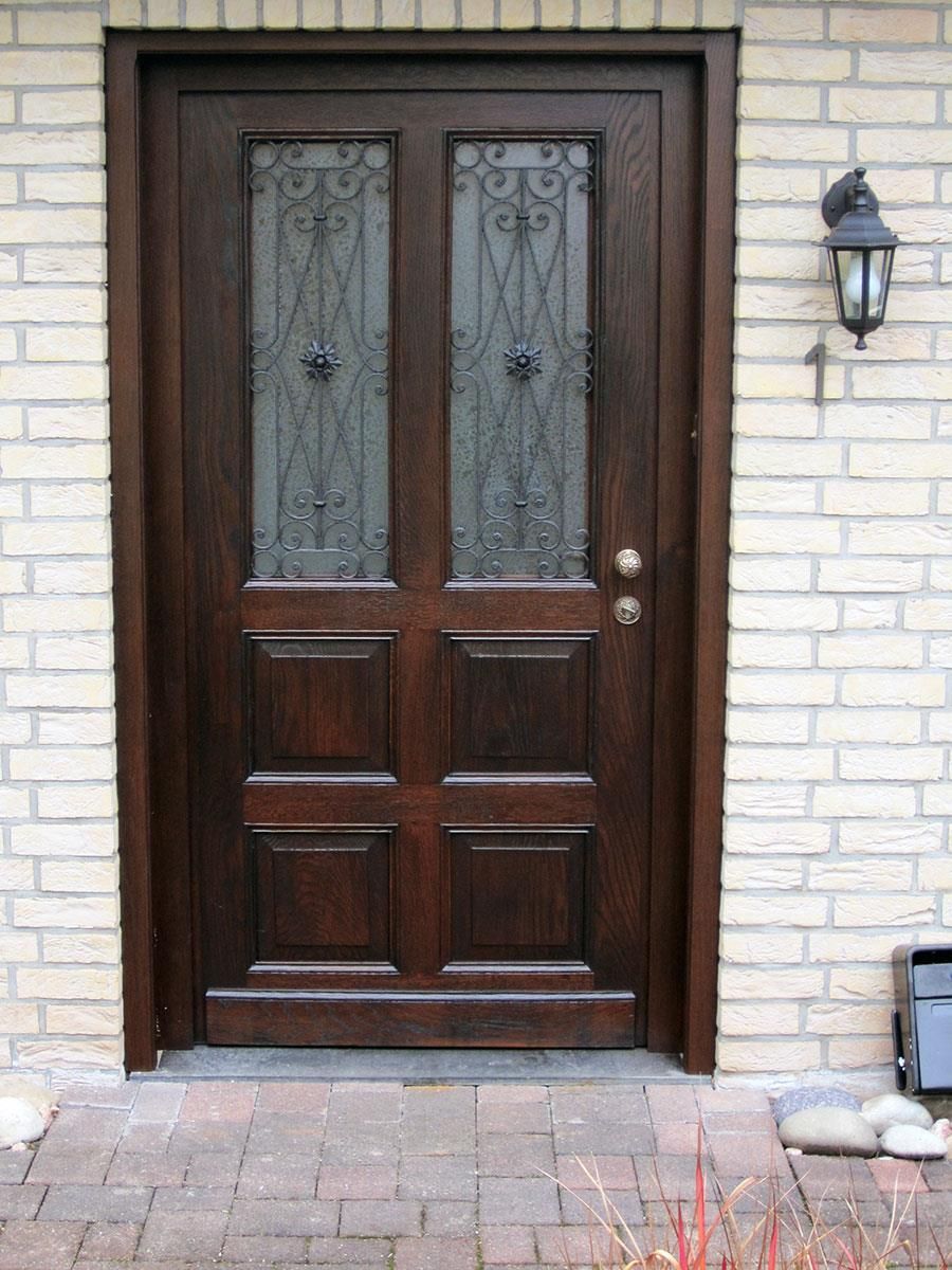 Ein Backsteingebäude mit einer Holztür und einer Lampe an der Seite