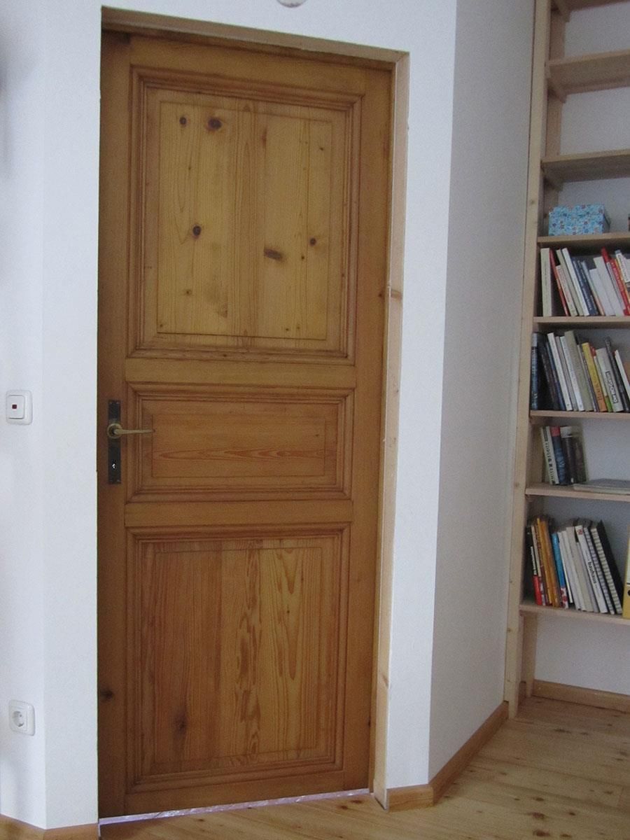 Eine Holztür in einem Raum neben einem Bücherregal