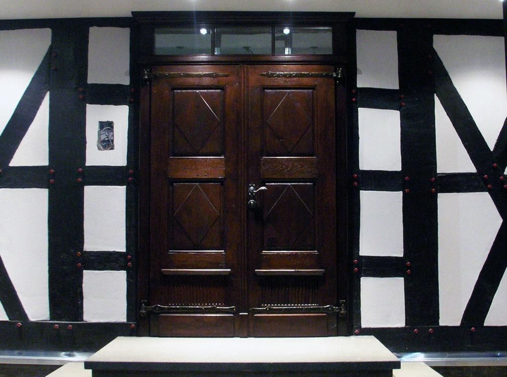 Ein schwarz-weißes Gebäude mit einer Holztür