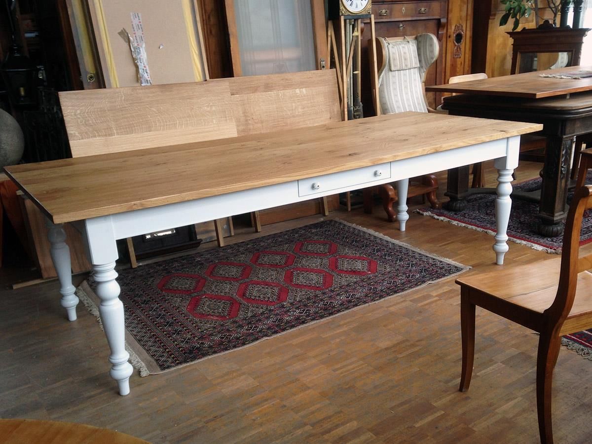 Ein Holztisch mit weißen Beinen und einem Teppich auf dem Boden