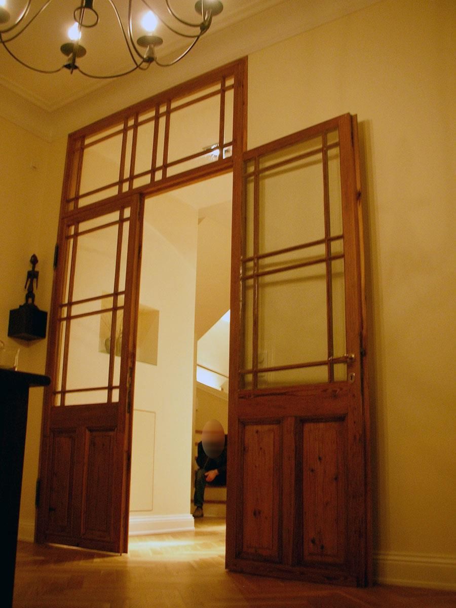 Ein Raum mit Holztüren und einem Kronleuchter, der von der Decke hängt