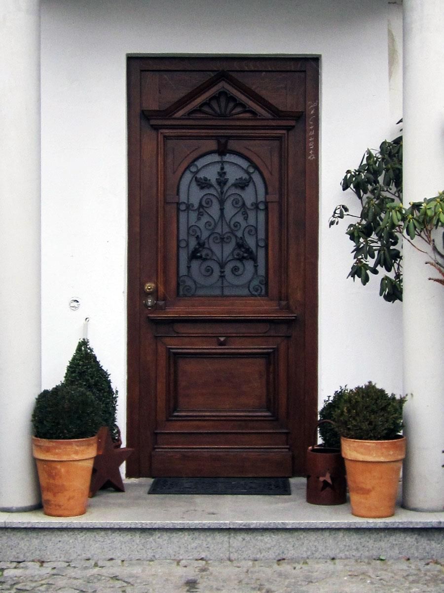 Eine Holztür mit einem schmiedeeisernen Fenster und Topfpflanzen davor