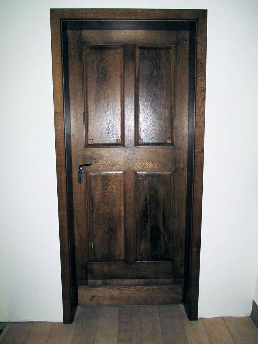 Eine Holztür mit einem Metallgriff steht vor einer weißen Wand