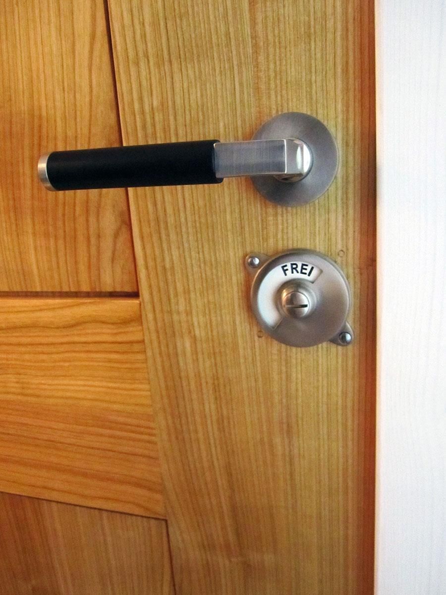 Eine Holztür mit einem schwarzen Griff und einem Edelstahlknauf mit der Aufschrift „Frei“