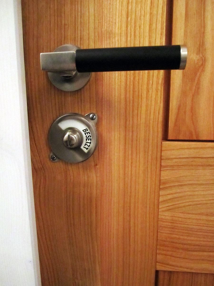 Eine Holztür mit einem schwarzen Griff und einem runden Knauf mit der Aufschrift „Gesetz“