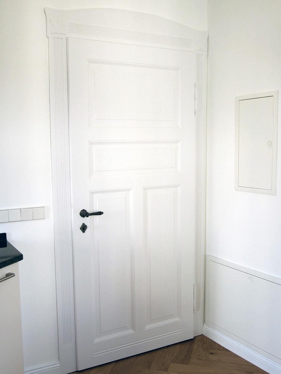 Eine weiße Tür mit einem schwarzen Griff in einem Zimmer