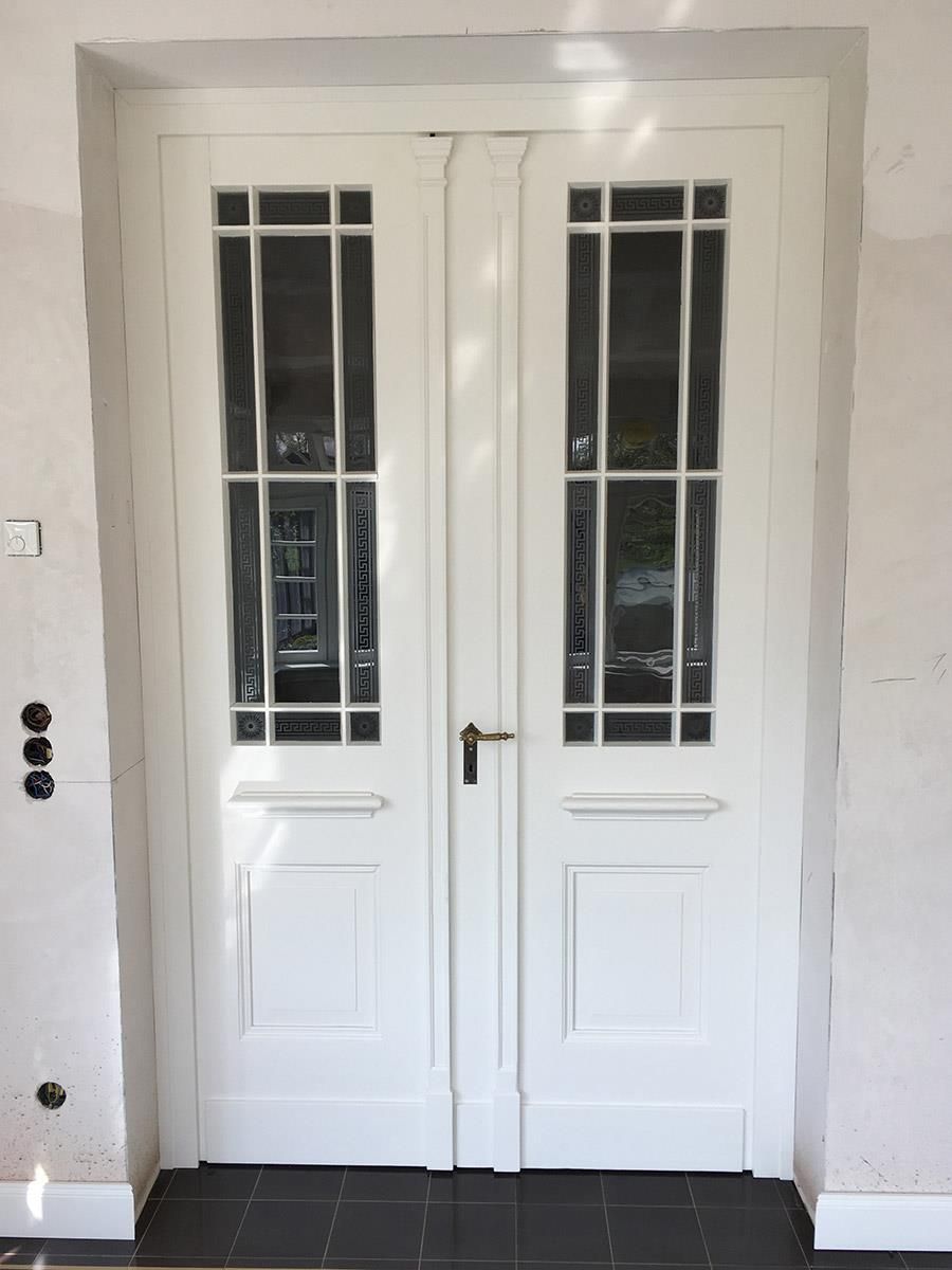 Ein Paar weiße Türen mit einem schwarzen Fliesenboden