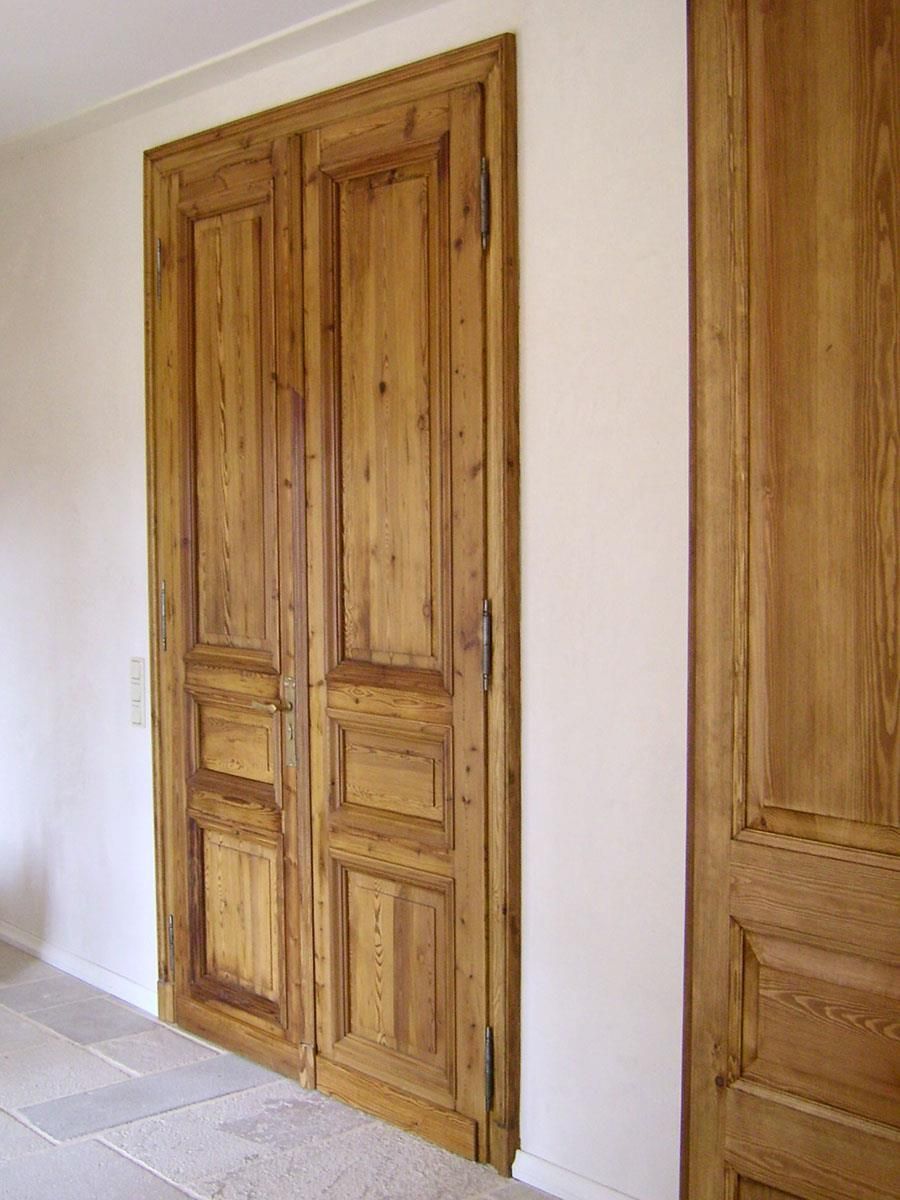 Ein Flur mit Holztüren und einer weißen Wand