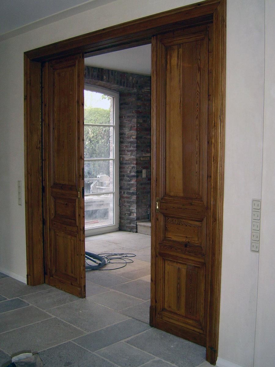 Eine Holztür führt zu einem Raum mit einer Ziegelwand