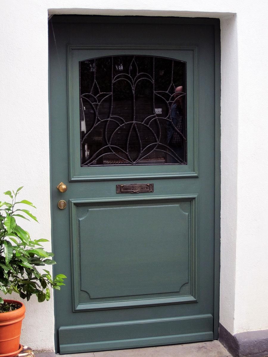 Eine grüne Tür mit einem Buntglasfenster