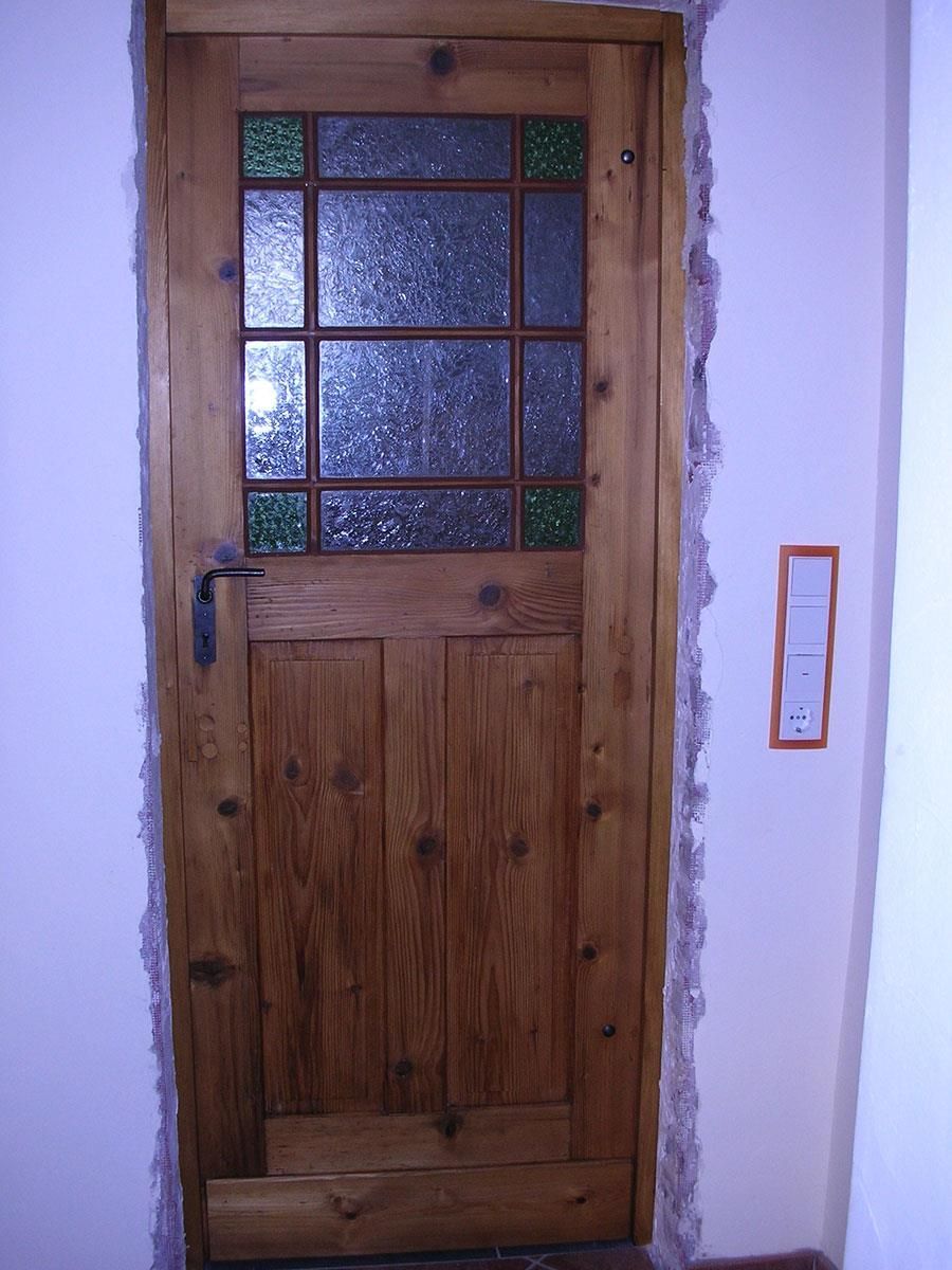 Eine Holztür mit einem Buntglasfenster