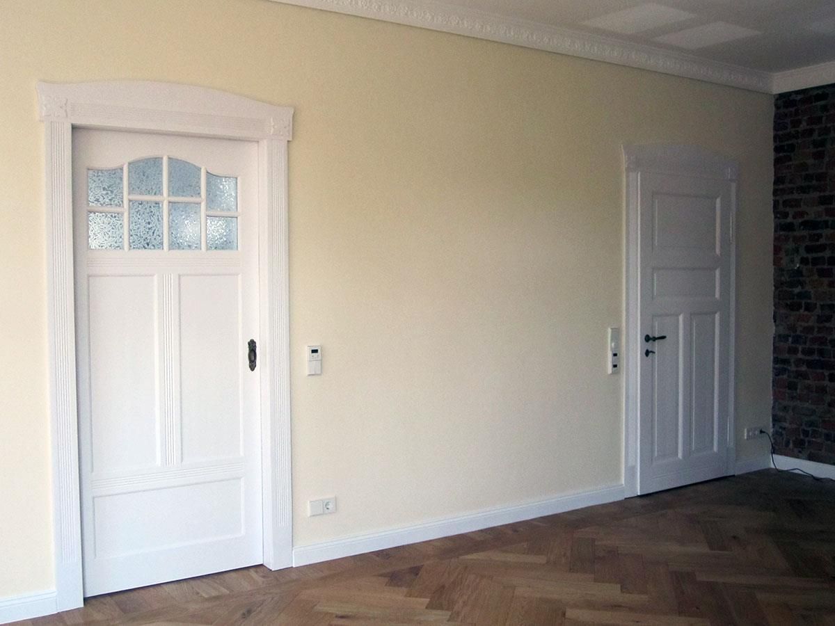 Ein leerer Raum mit zwei weißen Türen und einer Ziegelwand