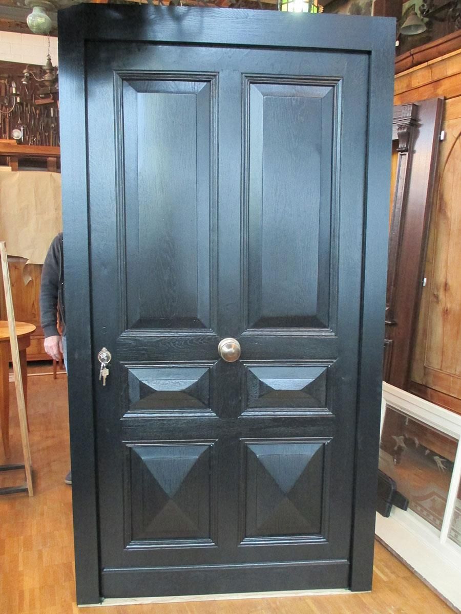 Ein Mann steht hinter einer schwarzen Tür in einem Raum