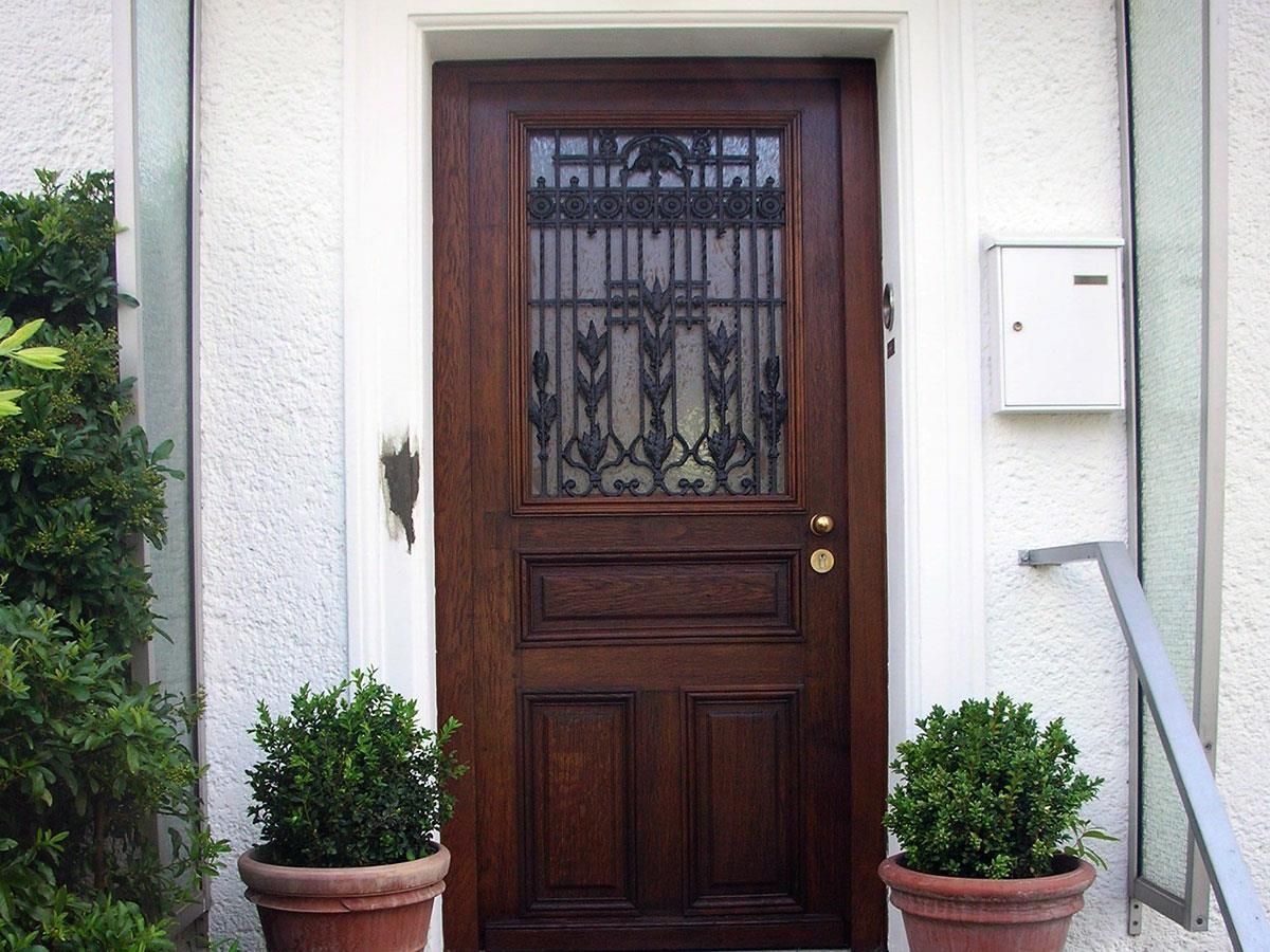 Zwei Topfpflanzen stehen vor einer Holztür