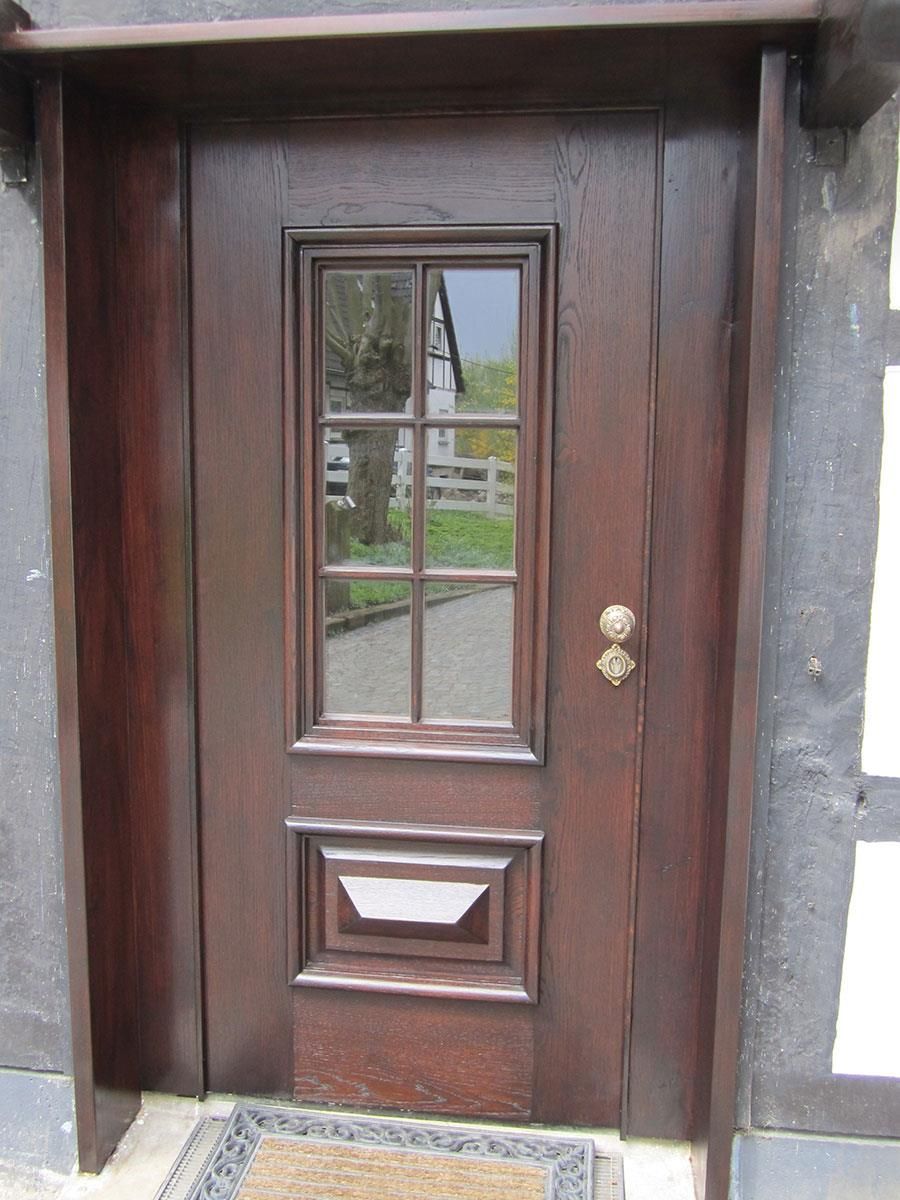 Eine Holztür mit der Spiegelung eines Hauses im Fenster