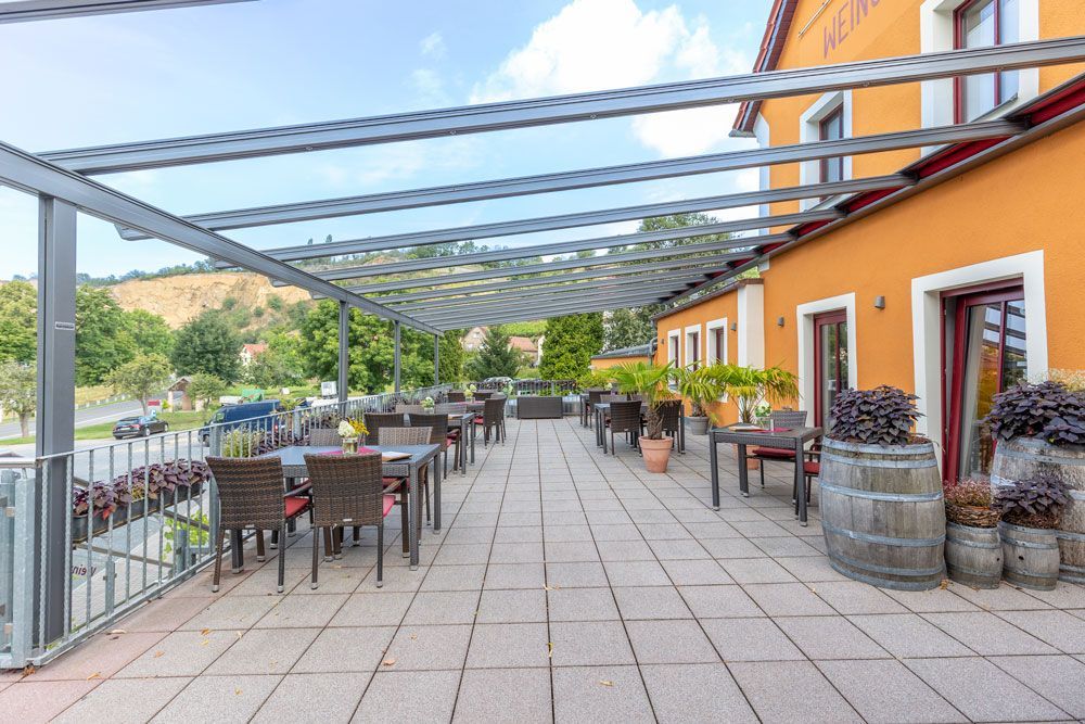 Eine große Terrasse mit Tischen und Stühlen unter einem Baldachin.