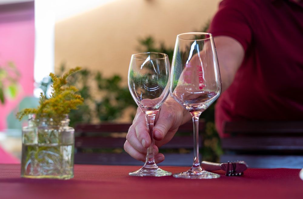 Eine Person hält zwei Weingläser auf einem Tisch.