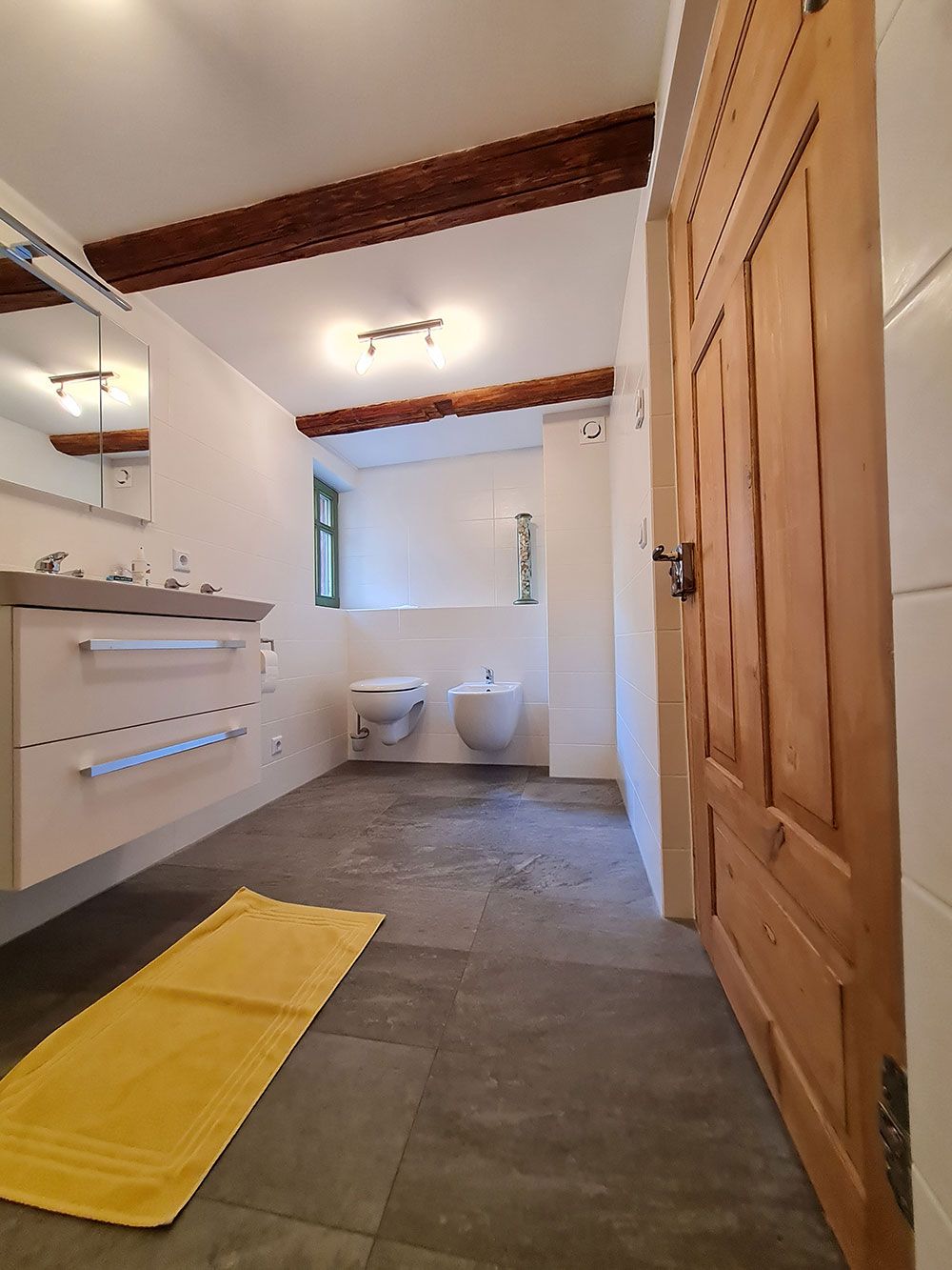 Ein Badezimmer mit einem gelben Teppich und einer Holztür.