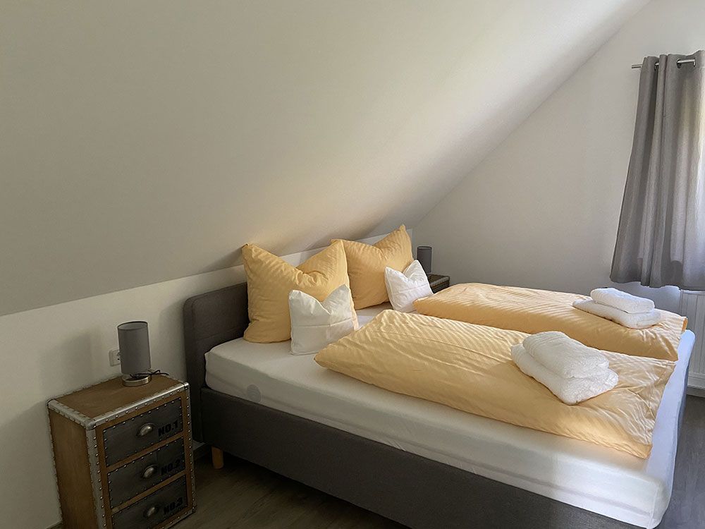 Ein Schlafzimmer mit zwei Betten, einem Nachttisch und einem Fenster.