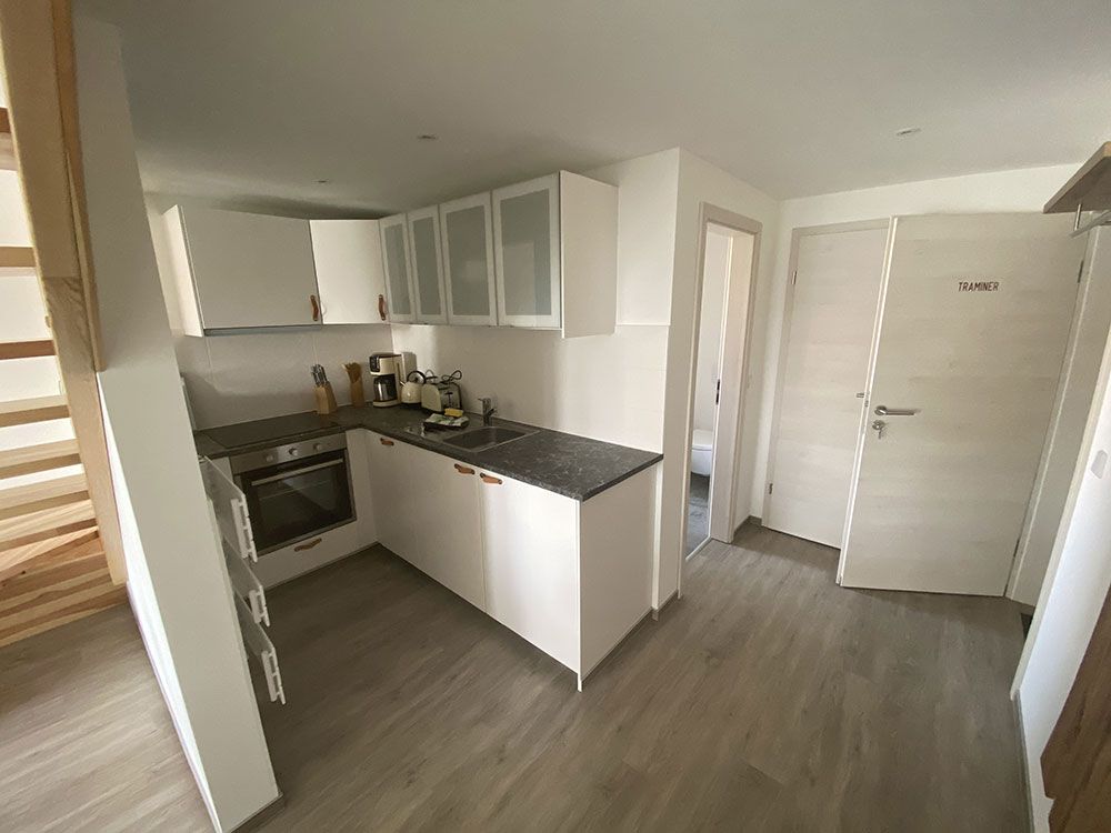 Eine Küche mit weißen Schränken und einer schwarzen Arbeitsplatte.