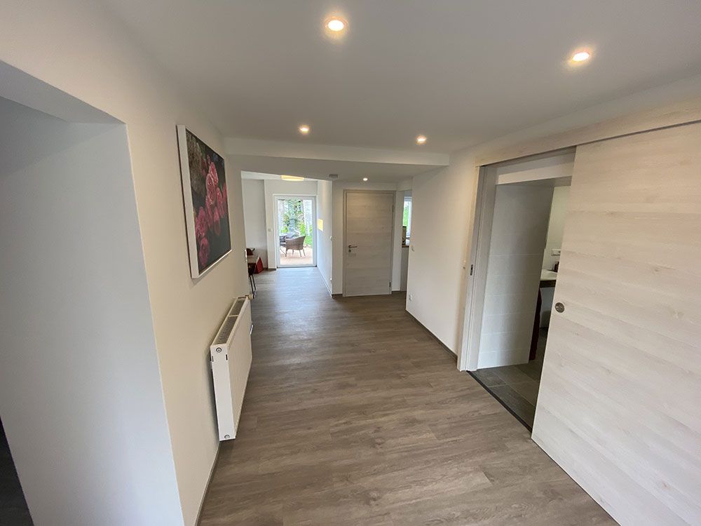 Ein langer Flur mit einer Schiebetür und einem Bild an der Wand.