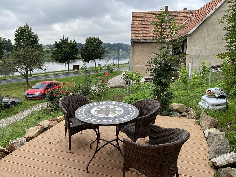 Ein Tisch und Stühle auf einer Terrasse mit Blick auf einen See.