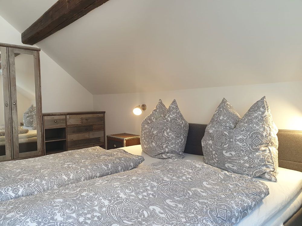 Ein Schlafzimmer mit Bett, Kommode, Nachttisch und Spiegel.