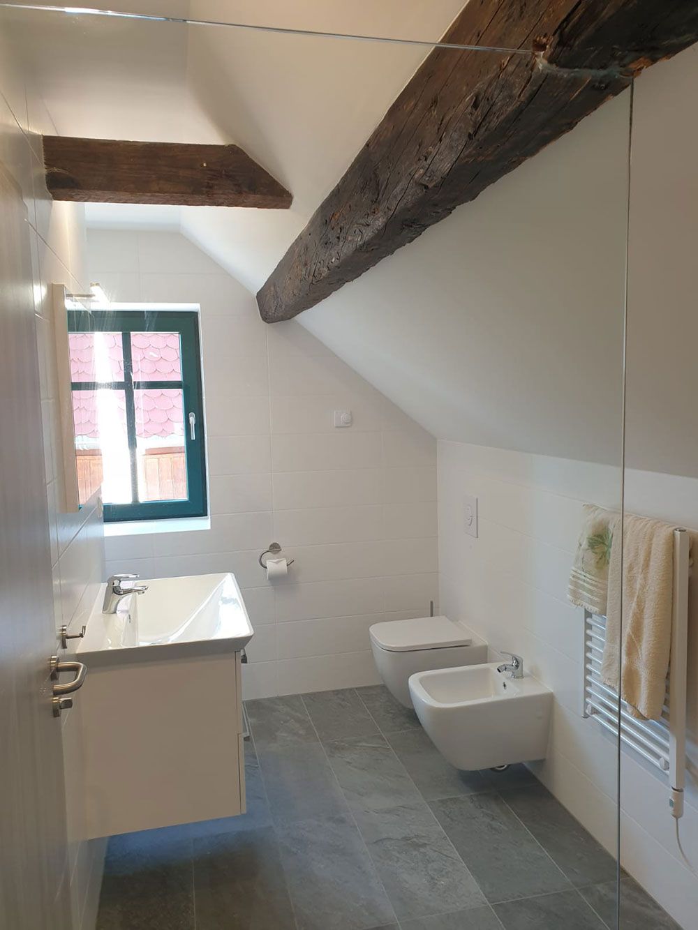 Ein Badezimmer mit Waschbecken, Toilette, Bidet und Fenster.